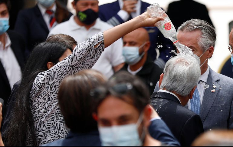Mujer lanza agua al presidente de Chile durante acto público.